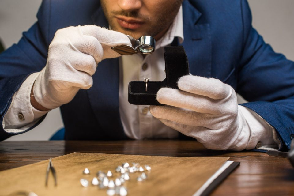 cropped-view-jewelry-appraiser-with-magnifying-glass-examining-gemstone-ring-table-grey-1-scaled-1-960x641.jpg